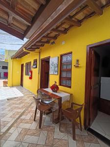 a room with a yellow wall with a table and chairs at Pousada da Tom-Ubatuba Perequê-Açu in Ubatuba