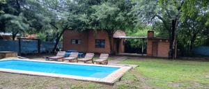 a swimming pool with lounge chairs and a house at Finca La Huella II in Santiago del Estero