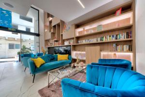 a living room with blue couches and bookshelves at Flamingo Hotel Malta in St. Julianʼs
