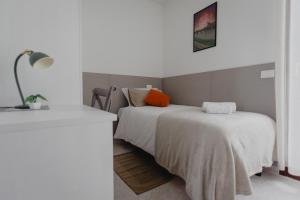 a white bedroom with two beds and a lamp at Casa Dama in Casaleone
