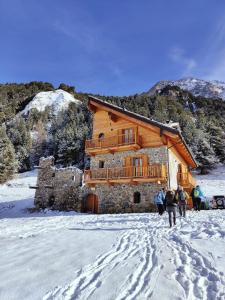 a group of people standing in the snow in front of a building at Rifugio Combe D'Imbert Vittoria in Champ Quartier +6 photos
