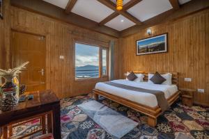 a bedroom with a bed and a large window at Gadegal Homestay Narkanda - Rooms & Pahadi Café in Shimla