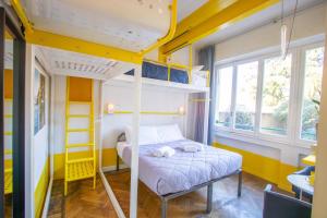 a bedroom with bunk beds with yellow walls and windows at Ostello Bello Lake Como in Como