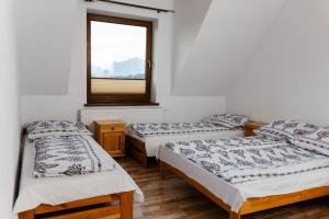 three beds in a room with a window at Pokoje u Jozka-Widok na Tatry in Groń