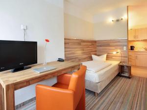 a hotel room with a bed and a desk with a television at Petul Apart Hotel City in Essen