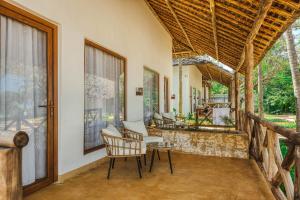 a room with a porch with chairs and a table at Tanzanite Beach Resort and Spa in Nungwi