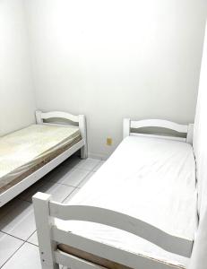 two beds in a small room with white walls at Cond Cristo Redentor in Trindade