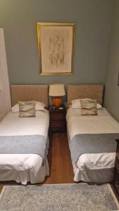 a room with two beds and a lamp in it at Maybank Guest House in Helensburgh