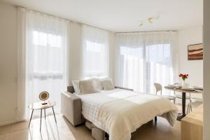 a white bedroom with a bed and a table at Regalia Suites - Free Parking in Lugano +63 photos