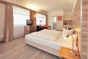 a hotel room with a large bed and a desk at Petul Apart Hotel City in Essen