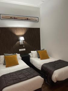 two beds in a hotel room with yellow pillows at Total Valencia Elegance in Valencia