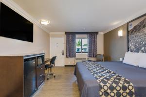 a hotel room with a bed and a flat screen tv at Hotel Seville - Ontario Airport/Chino in Ontario