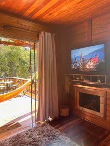 a living room with a television and a fireplace at Chalé Girassol in Venda Nova do Imigrante