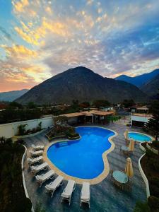 a resort with a pool and chairs and a mountain at Regina Hotel in Lunahuaná