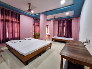a bedroom with two beds and a wooden table at Hotel New Castle in Guwahati