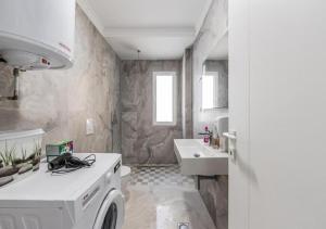 a bathroom with a sink and a washing machine at Relax Seafront Apartment by PS in Golem +22 photos