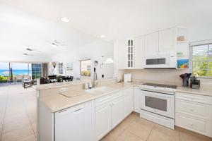 a kitchen with white cabinets and a view of the ocean at Northern Lights #6 Condo in Old Man Bay