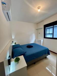 a bedroom with a blue bed and a window at Apê Ásia in Governador Celso Ramos
