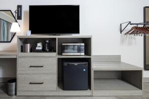 a wooden entertainment center with a television and a desk at Aviator Suites Hotel Juneau Airport by Aspen Hotels in Juneau