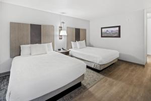 two beds in a hotel room with white sheets at Aviator Suites Hotel Juneau Airport by Aspen Hotels in Juneau