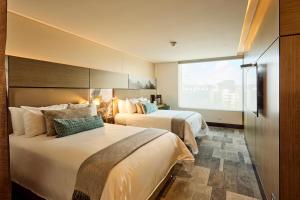 a hotel room with two beds and a large window at EK Hotel By Preferred Hotels Group in Bogotá
