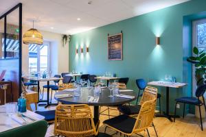 a restaurant with tables and chairs and a blue wall at L'Esplanade Hôtel Restaurant Bar à vin in Le Pellerin