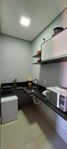 a kitchen with a counter top with a microwave at Vila Dumont no Centro de Foz in Foz do Iguaçu