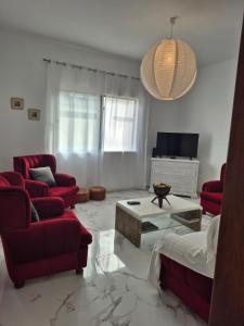 a living room with red chairs and a couch and a table at Villa Vista Norte in Porto Moniz