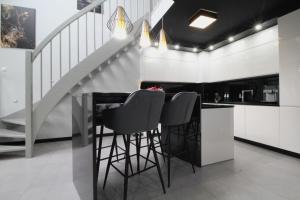 a kitchen with black bar stools and a staircase at Bulwar Apartament in Głogów