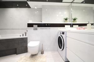 a bathroom with a toilet and a washing machine at Bulwar Apartament in Głogów +5 photos