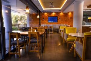 a restaurant with tables and chairs and a tv at Hotel Le Pelican in Asunción
