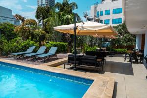 a patio with chairs and an umbrella and a pool at Hotel Le Pelican in Asunción