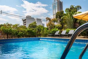 a swimming pool with chairs and buildings in the background at Hotel Le Pelican in Asunción