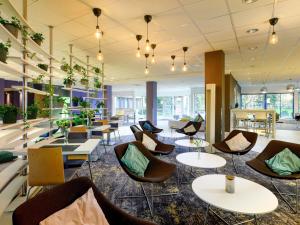 eine Lobby mit Stühlen, Tischen und Pflanzen in der Unterkunft Novotel Gdansk Centrum in Danzig