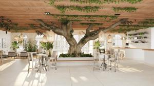 a tree in the middle of a room with tables and chairs at Luxury Resort e Hotel Ltda in Jericoacoara
