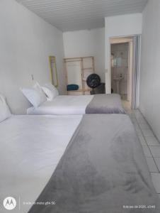 una camera da letto con due letti con lenzuola bianche di Espaço5-39 a Maceió
