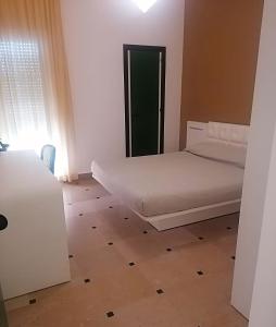 a small bedroom with a bed and a wooden floor at Hyencos Hotel Calos in Torre San Giovanni Ugento