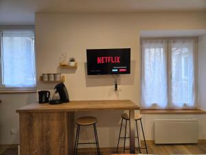 a kitchen with a counter with stools and a tv on the wall at Le Sebastopol- Studio cosy en centre ville de Brioude in Brioude