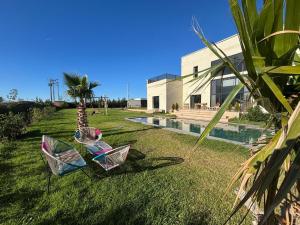 two chairs sitting in the grass next to a pool at Luxury Villa Lam atlas view in Marrakesh