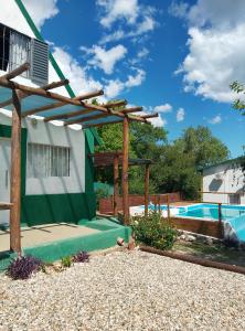 a pergola in front of a house with a pool at CABAÑAS L y L in Villa Santa Cruz del Lago