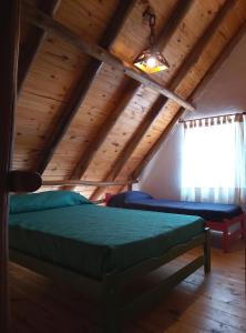 a bedroom in a log cabin with a bed and a window at CABAÑAS L y L in Villa Santa Cruz del Lago +13 photos