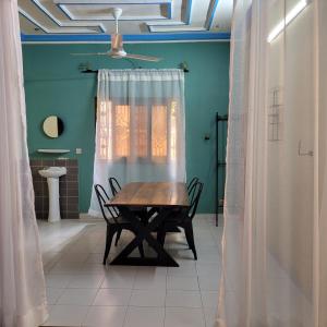 ein Tisch und Stühle in einem Zimmer mit Fenster in der Unterkunft Maison Altra in Bobo-Dioulasso
