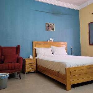 ein Schlafzimmer mit einem Bett und einem roten Stuhl in der Unterkunft Maison Altra in Bobo-Dioulasso