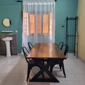 ein Holztisch und Stühle in einem Zimmer mit Fenster in der Unterkunft Maison Altra in Bobo-Dioulasso
