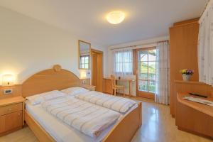 a bedroom with a large bed and a desk at Vogelmaierhof am Kalterer See in Caldaro