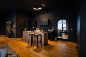 a kitchen with black walls and a white island with bar stools at Sunset Penthouse Antwerp in Antwerp
