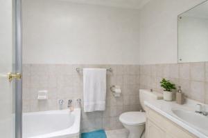 a bathroom with a toilet and a tub and a sink at Modern 2BR Apartment North Adelaide in North Adelaide +3 photos