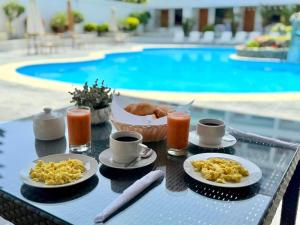 a table with breakfast foods and drinks on a table by a pool at Regina Hotel in Lunahuaná