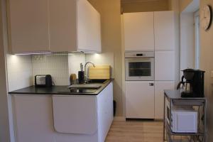 a kitchen with white cabinets and a black counter top at Borg Kiertokatu, Spacious Studio Apt, Free Parking in Pori