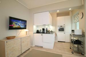 a kitchen with white cabinets and a tv on the wall at Borg Kiertokatu, Spacious Studio Apt, Free Parking in Pori